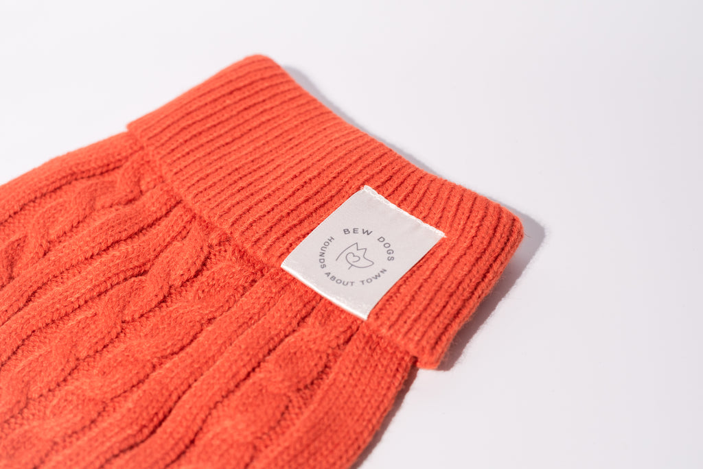 A close up on a Burnt orange cable knit dog jumper with Bew Dogs label and ribbed neckline for small dogs 