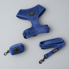 A deep blue velvet walking set for dogs including harness soft velvet lead and matching poo bag holder - set against a grey studio background 