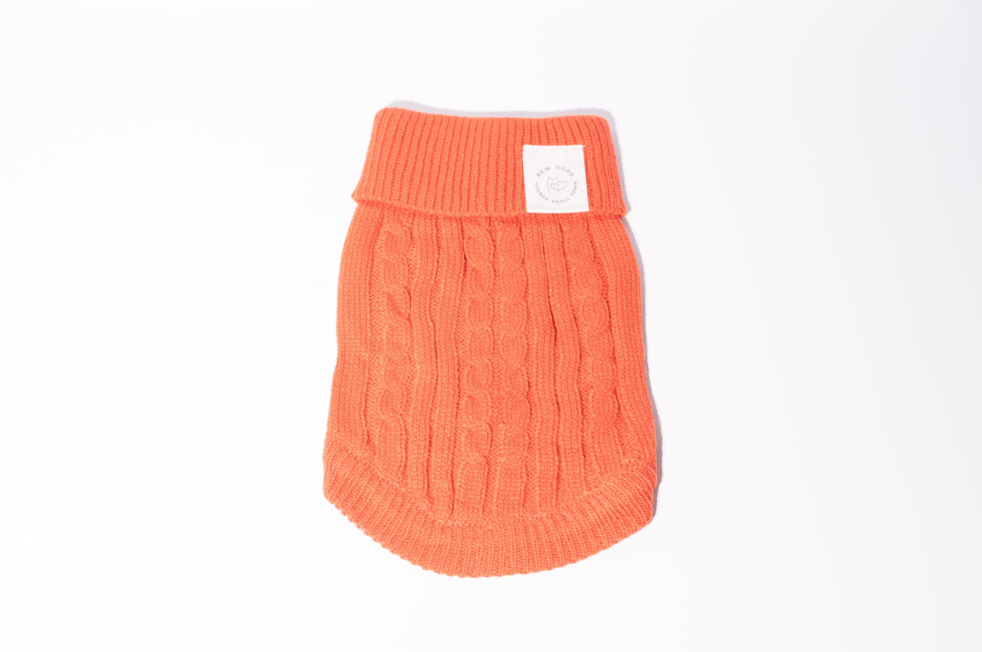 An orange cable-knit pet sweater with a ribbed collar and a small white brand patch, shown on a plain white background - perfect for small dogs and puppies 