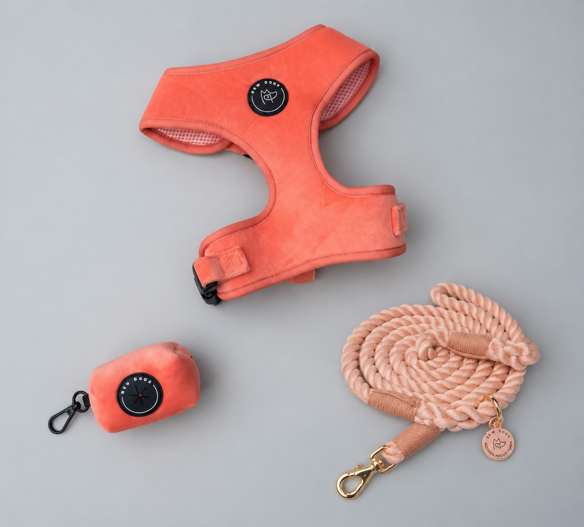 A peach coral orange velvet dog harness, matching poo bag holder pouch, and a thick peach rope lead with gold hardware, arranged on a light gray background - the perfect velvet walking set, suitable for large dogs 