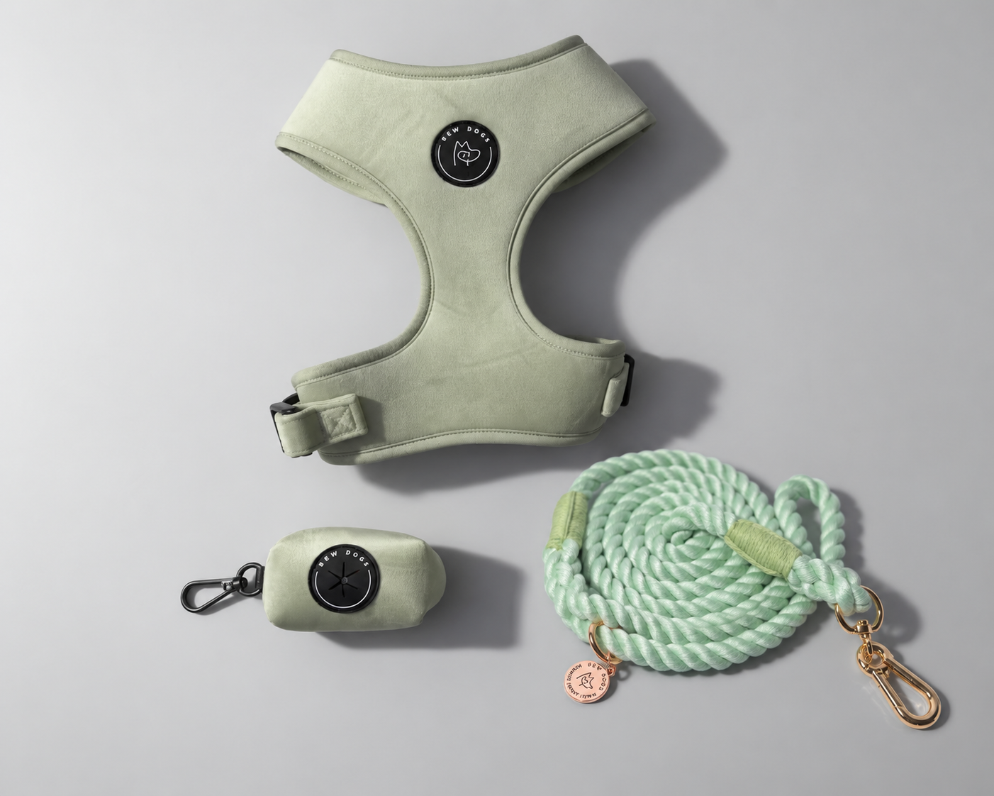 A dog walking harness set in pale sage green, including a green velvet harness, a small matching case to hold poo bags, and a thick mint green rope lead with gold-tone hardware, arranged on a light gray background - a sage green set for all dogs including size L & XL