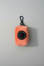 Peach velvet poo bag holder for dogs, studio shot against a grey background