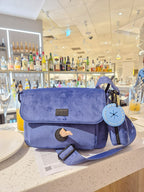 blue velvet dog walking bag, with multiplet compartments for poo bags, pool loop and treats, is sitting on top of a bar