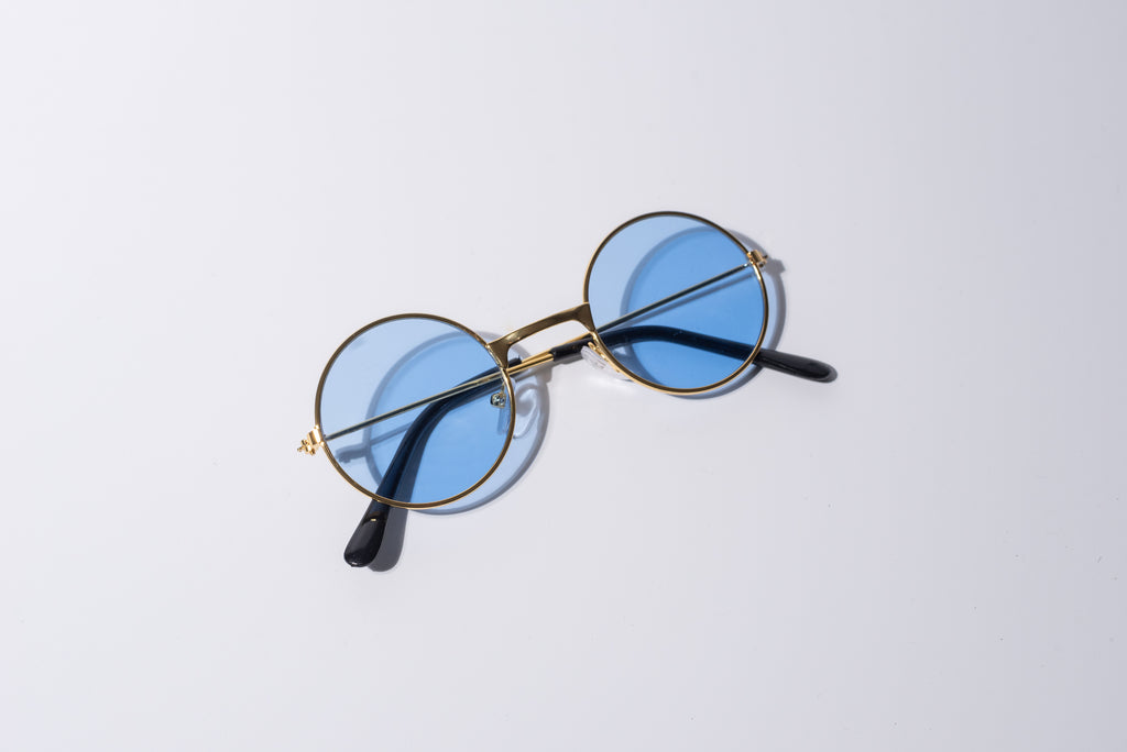 round blue lens sunglasses for dogs, with gold hardware sit against a white background