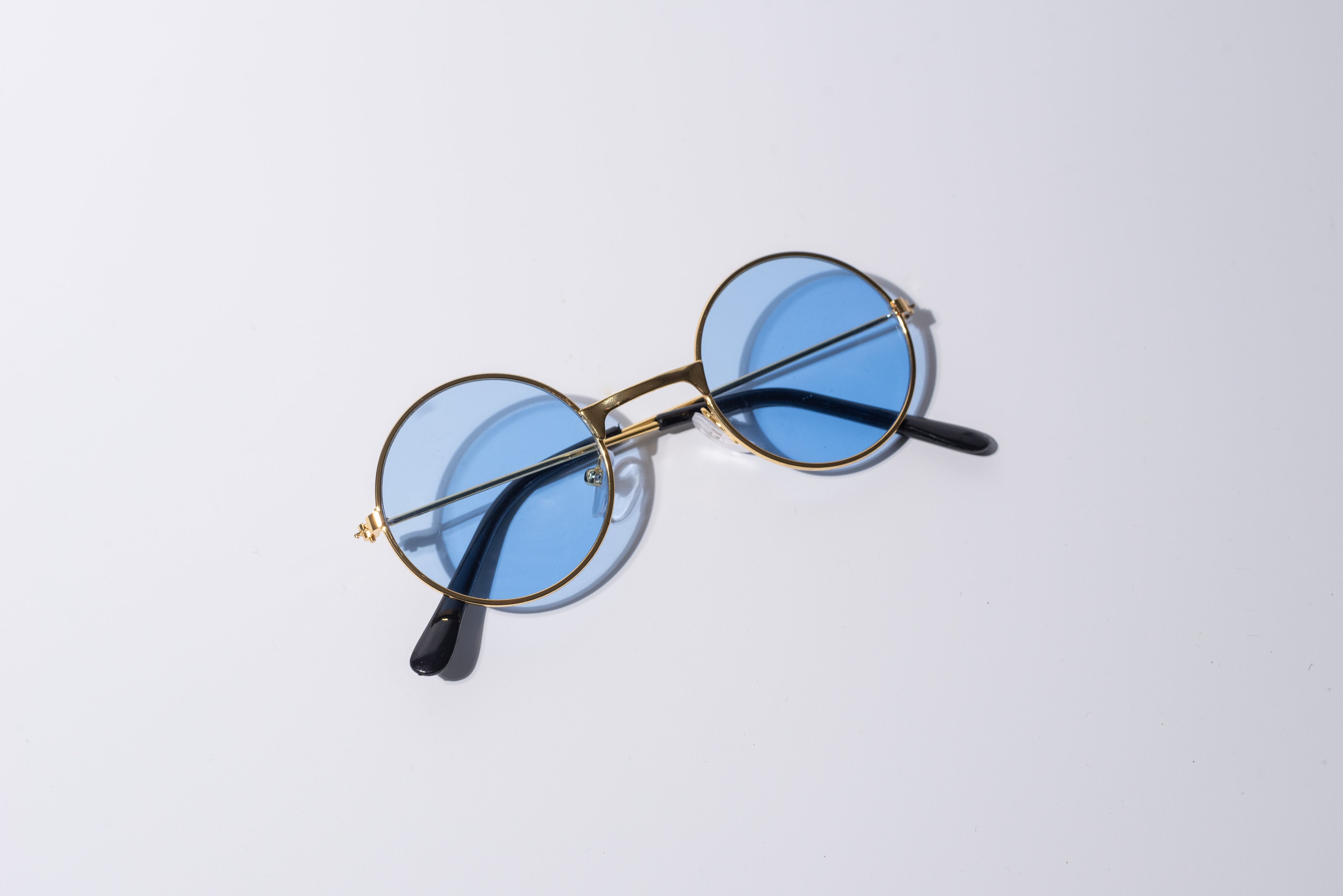 round blue lens sunglasses for dogs, with gold hardware sit against a white background