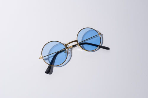 round blue lens sunglasses for dogs, with gold hardware sit against a white background