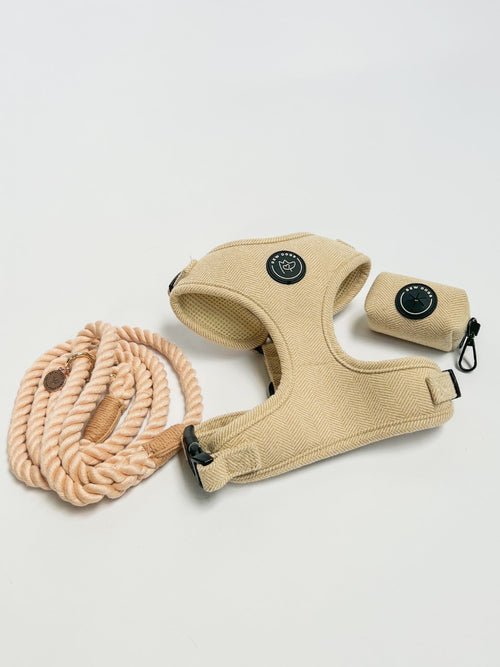 a cream dog harness walking set including soft herringbone harness, matching poo bag holder that clips on to the stylish cream rope lead. set against a soft grey studio background