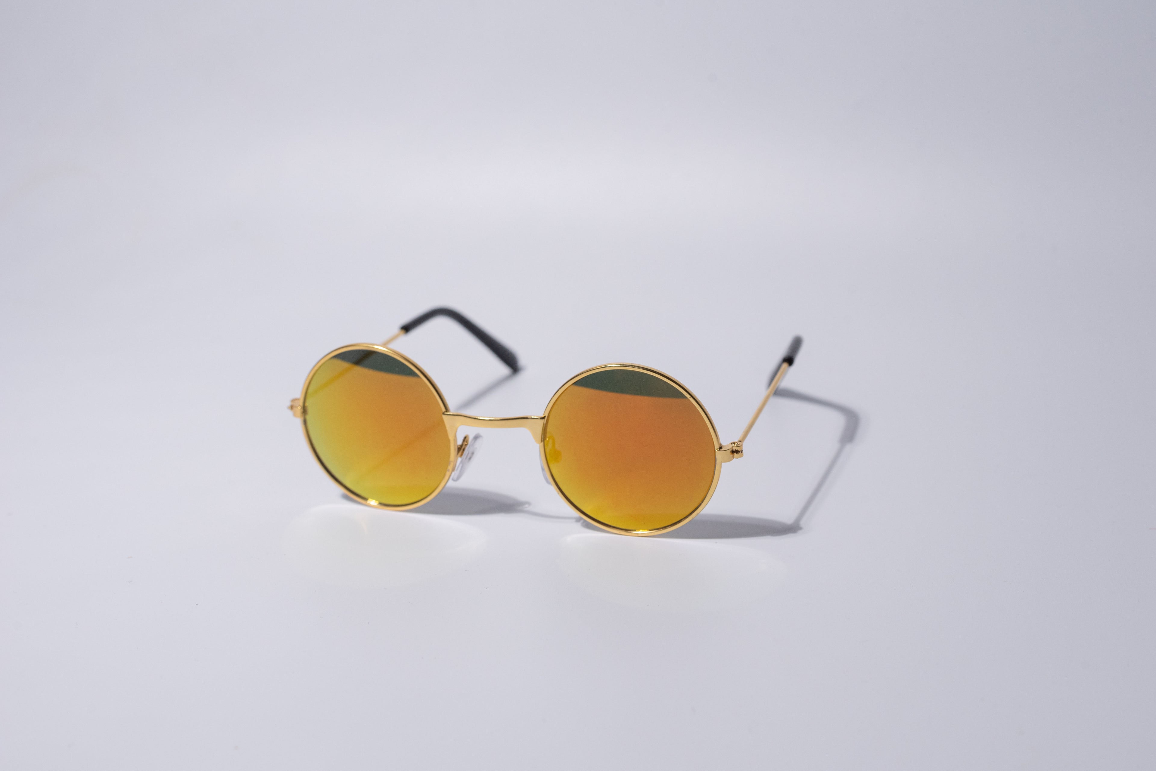 orange reflective, round sunglasses for cats and dogs sit on a grey background. 