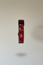 a festive red christmas collar in plaid material for dogs, shown against a grey backdrop