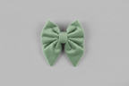 a soft, adjustable sage green velvet sailor bow for dogs, set against a grey background