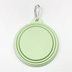 Light pastel green silicone dog bowl with a carabiner on a white background