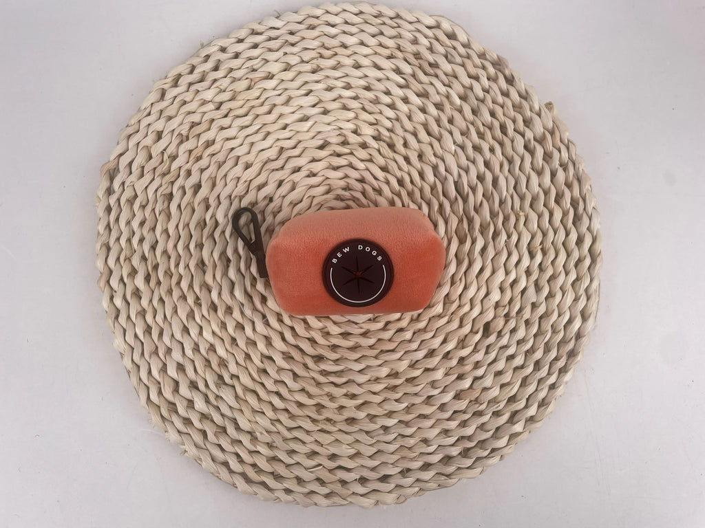 Sundown Collection dog poo bag holder, a must have dog walking accessory, is shown on a rope mat, against a grey background
