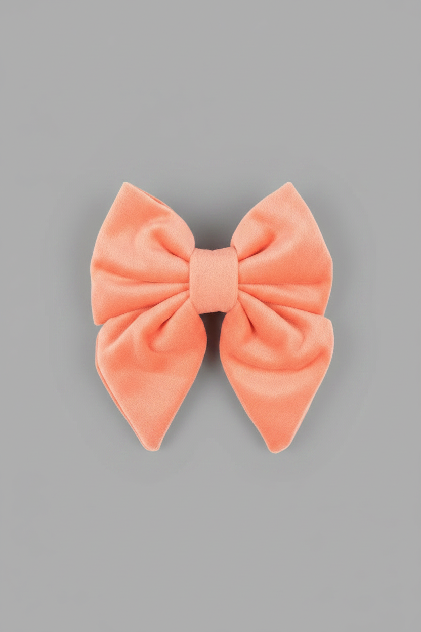 a soft, peach velvet sailor bow for dogs, against a grey background