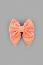 a soft, peach velvet sailor bow for dogs, against a grey background
