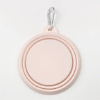 A light pink collapsible pet water bowl with a silver metal carabiner clip at the top, shown on a clean white background.