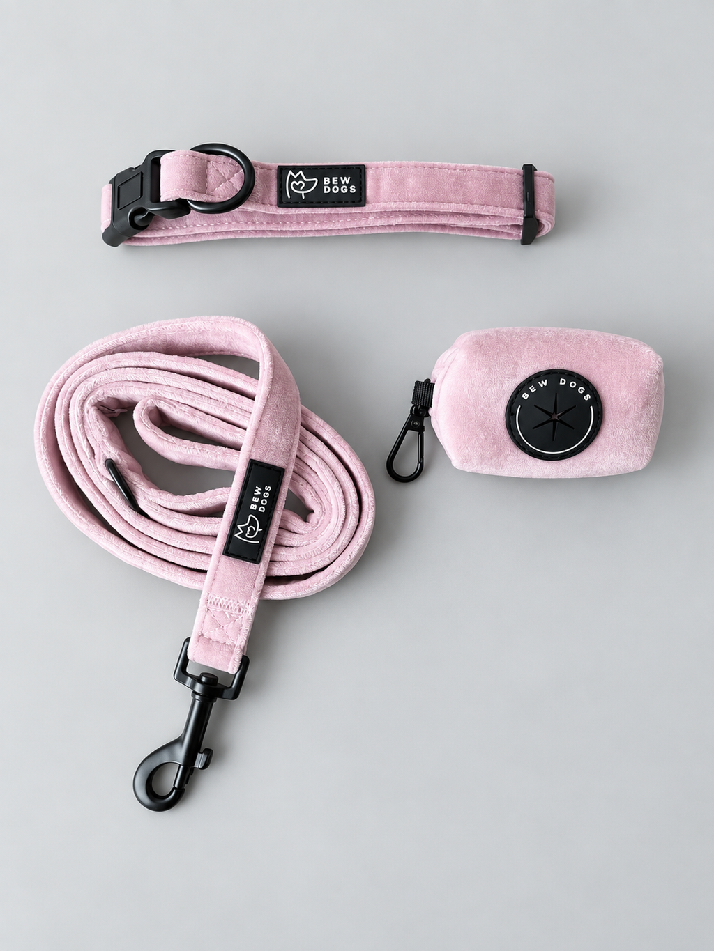 a soft pink velvet walking set for dogs, including adjustable collar, soft velvet lead and matching poo bag holder - set against a grey studio background