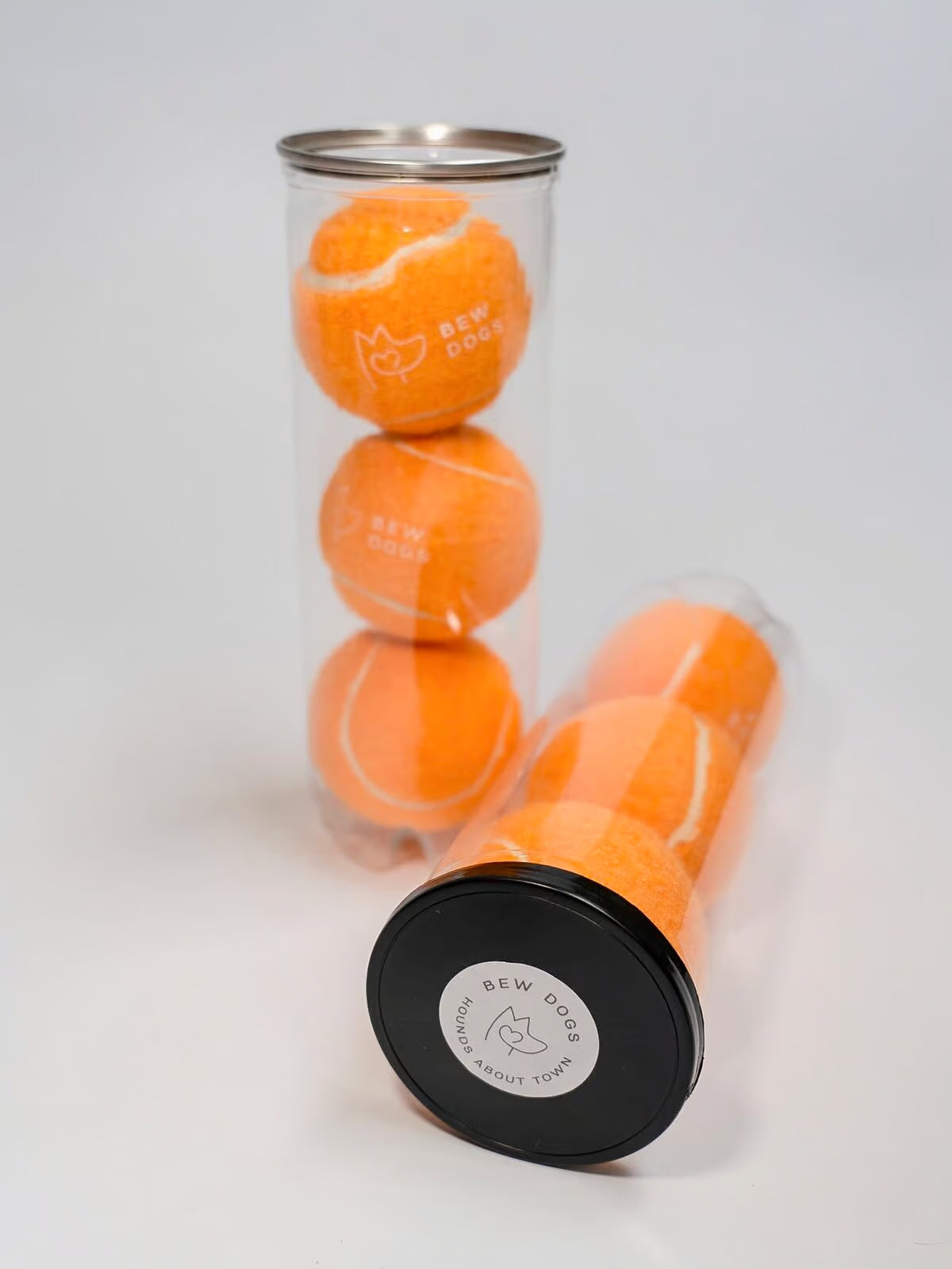 Orange tennis ball with black cap on a white background