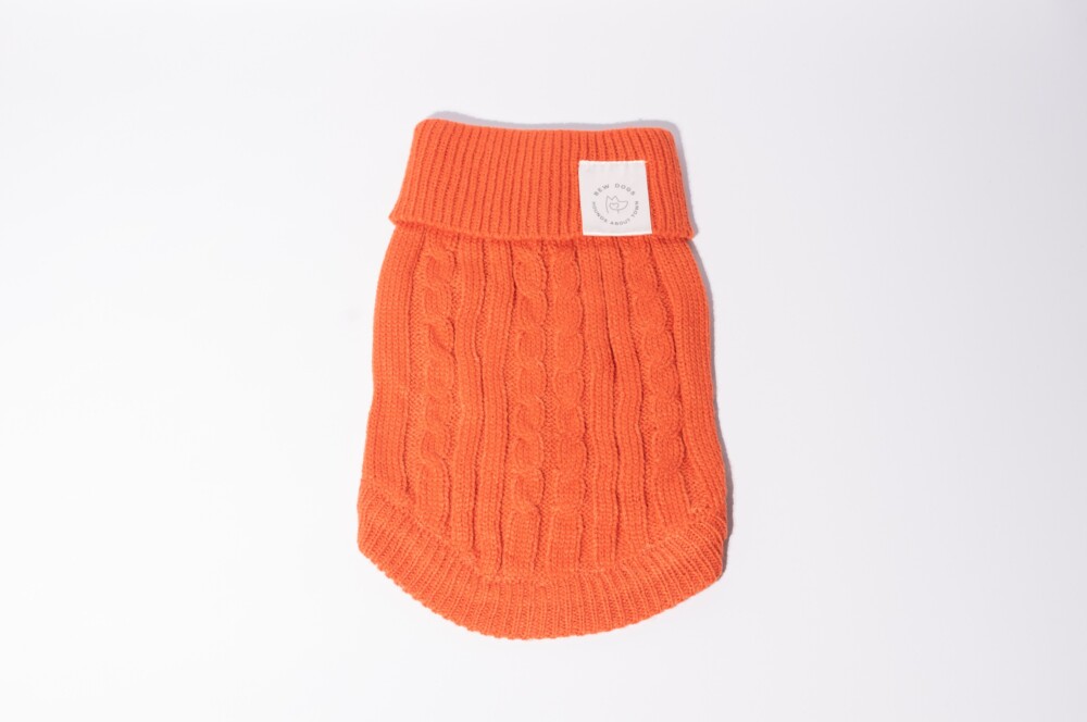 Am orange cable knit jumper on a white background