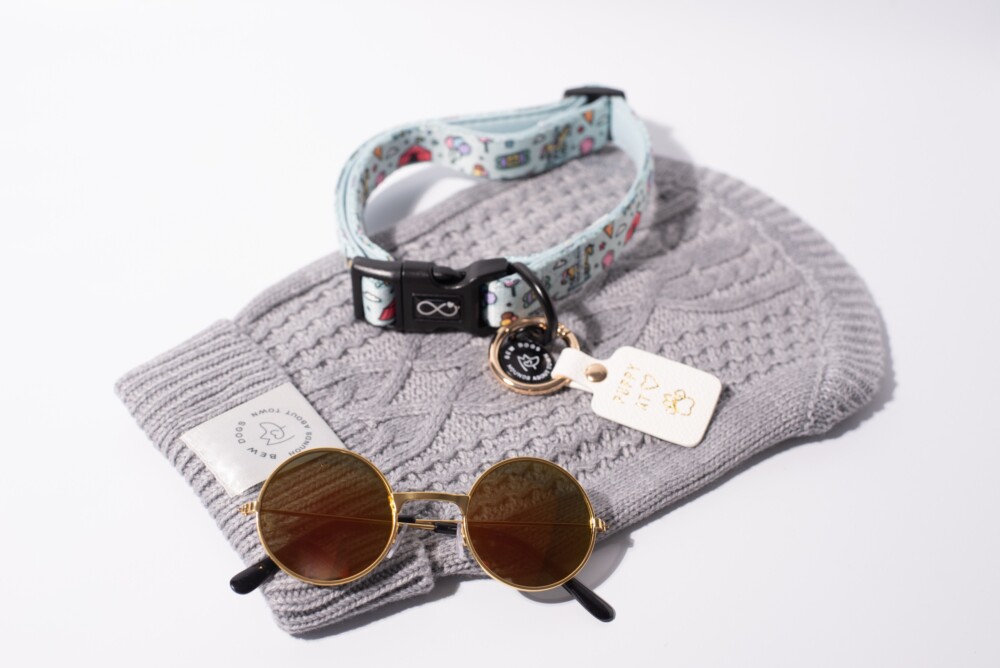 A bundle of items including a grey cable knit jumper, sunglasses and a dog collar.