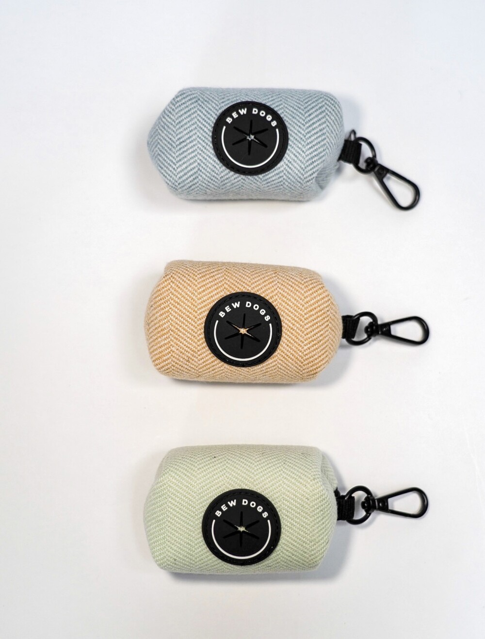 Three holders with clips to store poop bags in green, blue and cream