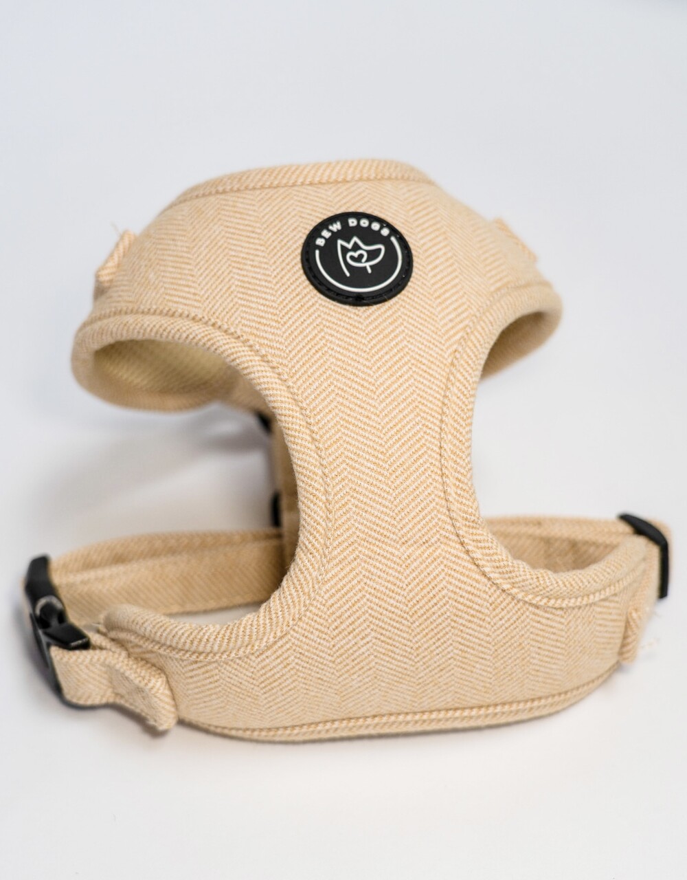 A cream herringbone dog harness with adjustable straps on a white background.