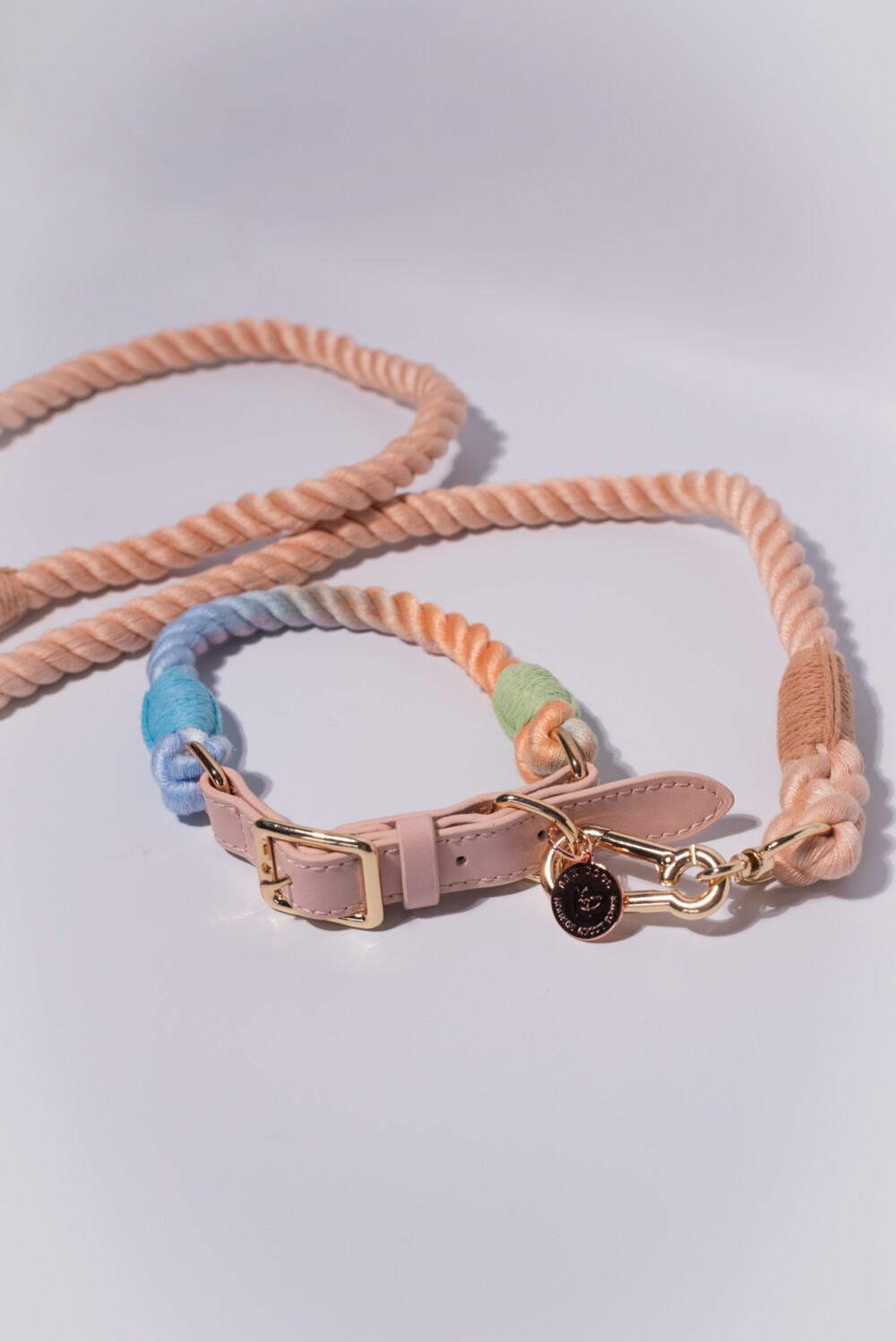 A peach rope lead and rainbow rope collar on a white background