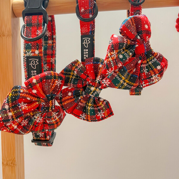 red christmas dog collars with matching bows in a festive pattern hanging from a wooden pole.