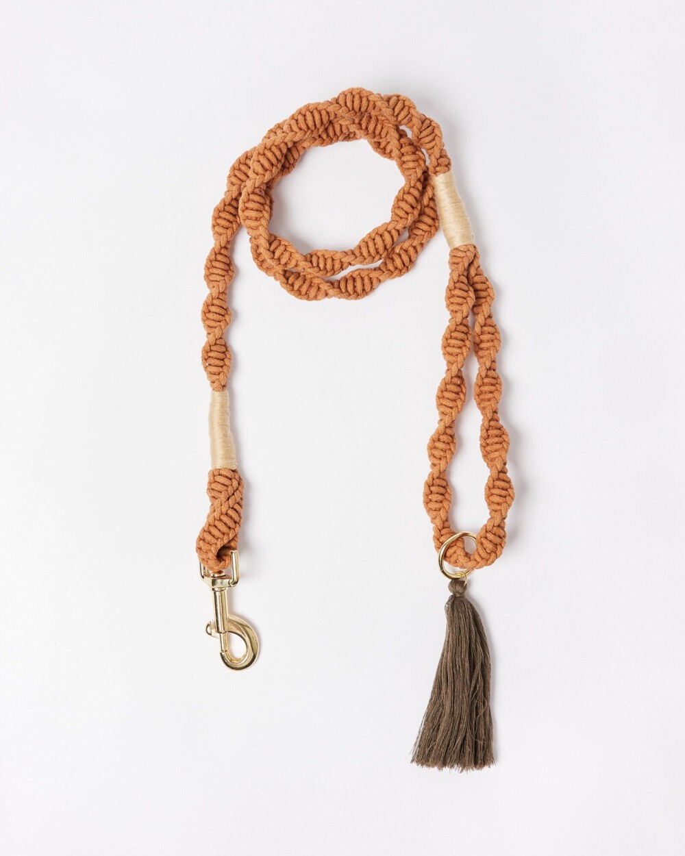 a orange/brown sunset coloured twister rope lead with a tassel and gold detail glasp, shown against a white background